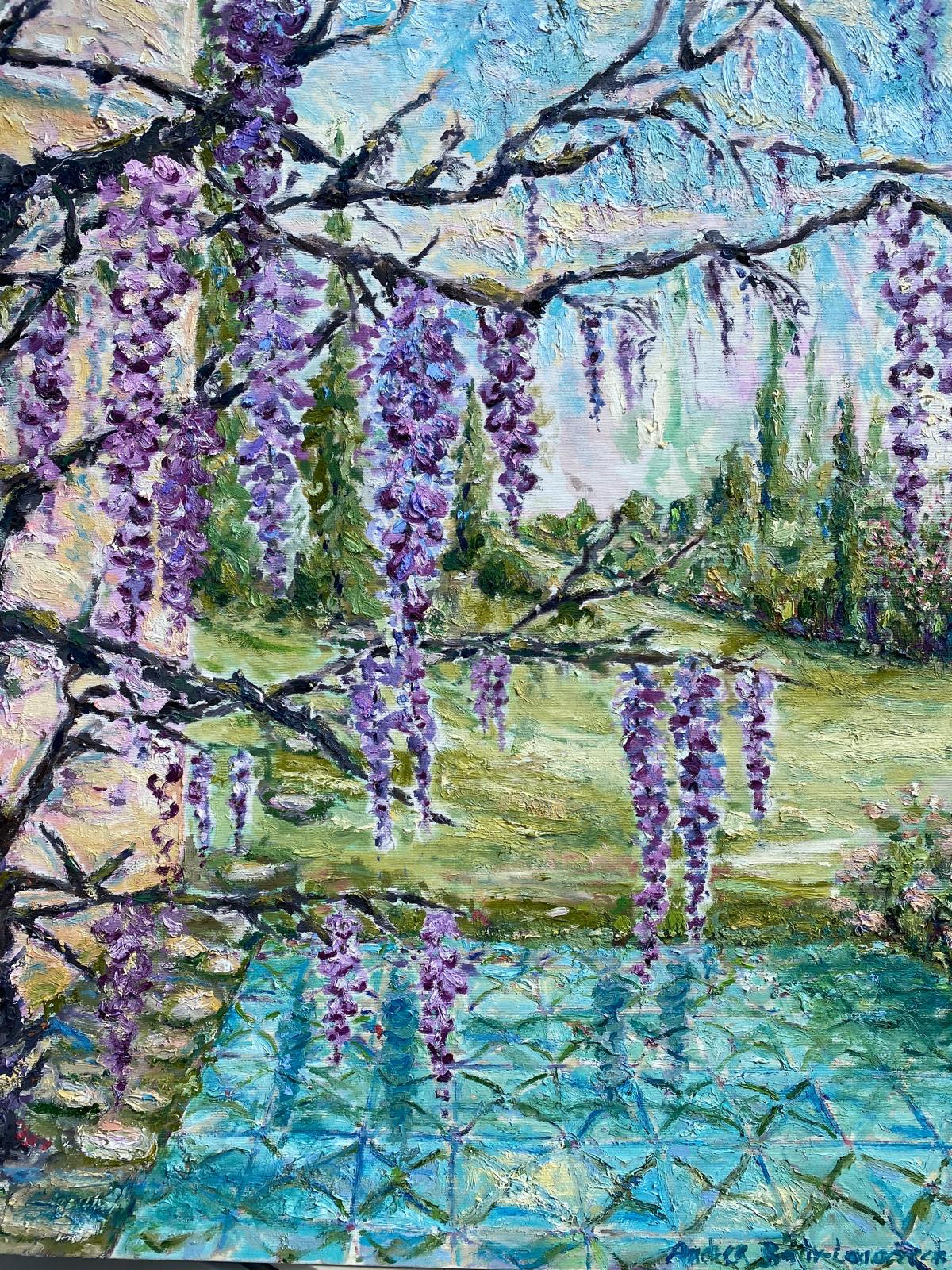 Violette Blauregentrauben hängen von dunklen Ästen, dahinter ein Garten mit Wiese und Zypressen